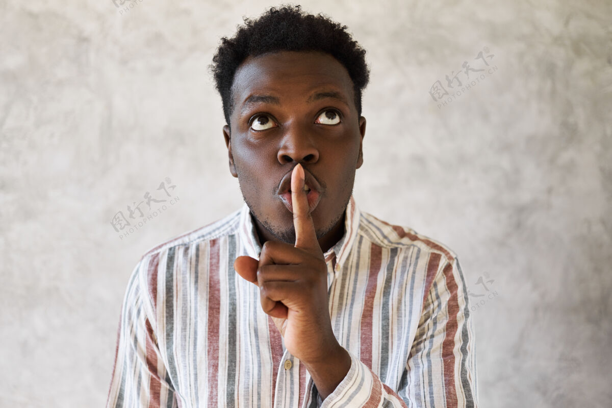 阴谋神秘的年轻非洲男人抬起头来 把食指放在嘴唇上停止秘密嘘