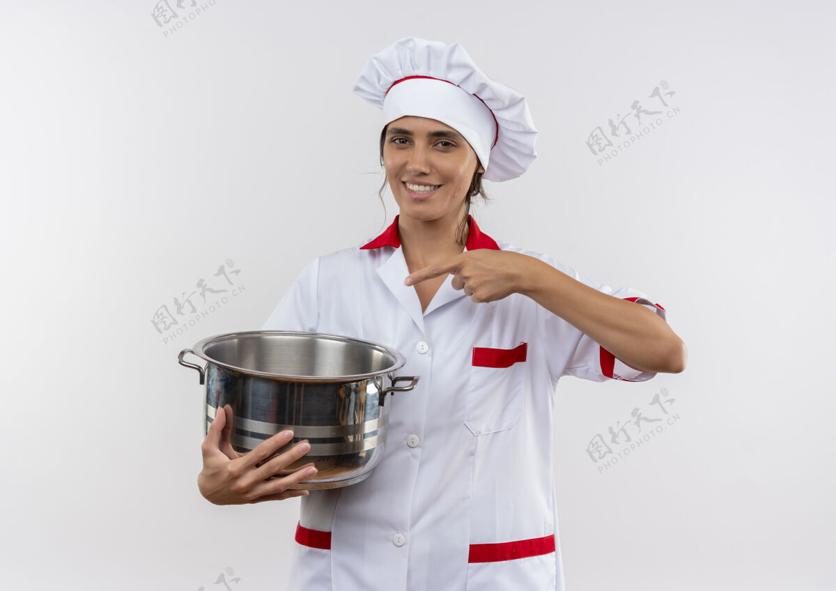 穿年轻的女厨师面带微笑 穿着厨师制服 拿着火锅指着有复印空间的地方厨师平底锅拿
