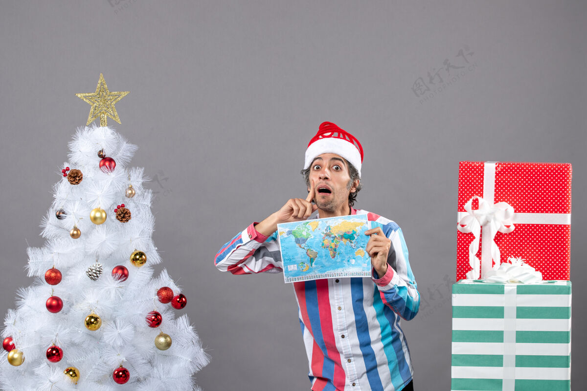 圣诞老人前视图有兴趣的男子与螺旋弹簧圣诞帽举行世界地图圣诞树可爱快乐