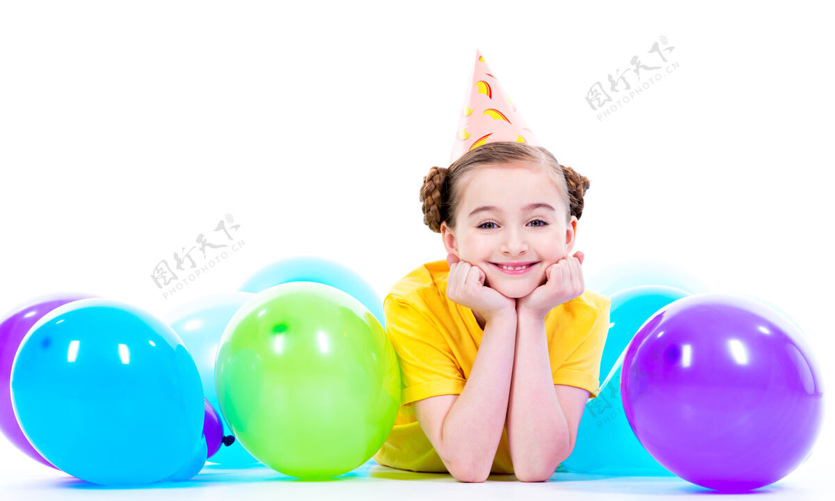 漂亮穿着黄色t恤的快乐微笑女孩躺在地板上 手里拿着五颜六色的气球——孤立在白色的地板上游戏积极孩子