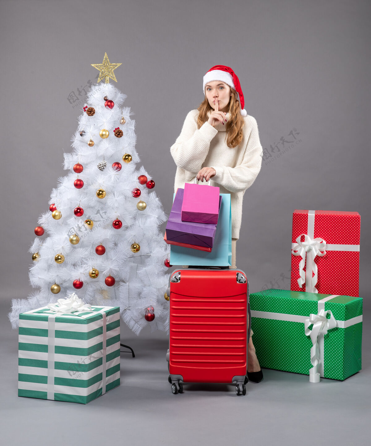 行李正面图金发女孩 戴着圣诞帽 手里拿着红色的手提包 购物袋上写着“嘘”金发女孩盒子圣诞老人