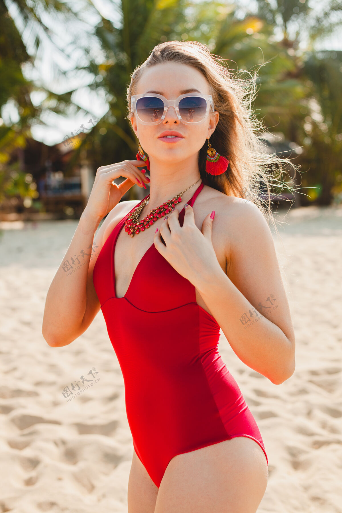 年轻年轻漂亮的金发女人穿着红色泳衣 戴着太阳镜在沙滩上晒太阳泳装休闲可爱