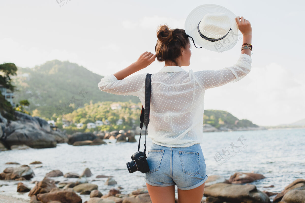 稻草在亚洲度暑假的年轻漂亮的时髦女人 在热带海滩上放松 数码相机 随意的波西米亚风格 海洋风景 苗条的棕褐色身体 独自旅行 自由衬衫自由漂亮