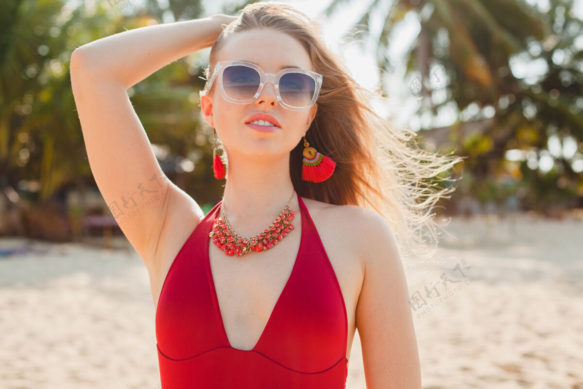 模型年轻漂亮的金发女人穿着红色泳衣 戴着太阳镜在沙滩上晒太阳可爱配件女士