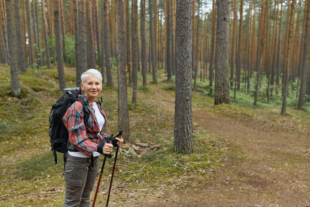 徒步旅行在国家公园里 穿着活动服的中年女性站在小路上 用杆子在北欧行走景观棍棒冒险