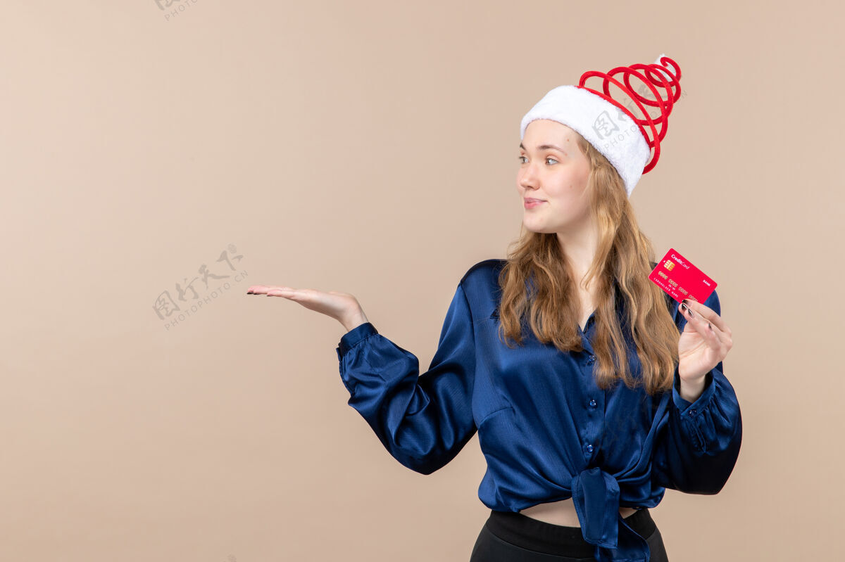 年轻正面图年轻女性手持红色银行卡上粉色背景钱度假照新年圣诞情感自由空间圣诞节女性年轻的女性