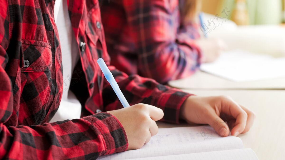 文书特写镜头：一个十几岁的女孩在做作业的时候拿着钢笔写字女性互联网人