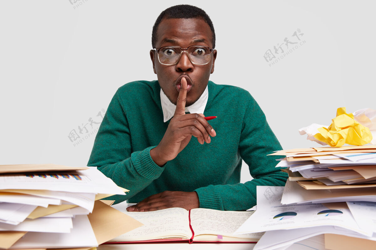 坐着秘密的非洲裔男ceo露出沉默的手势 在接到老板的任务上工作 把想法写在笔记本上 有着惊讶的表情耳语沉默工作场所