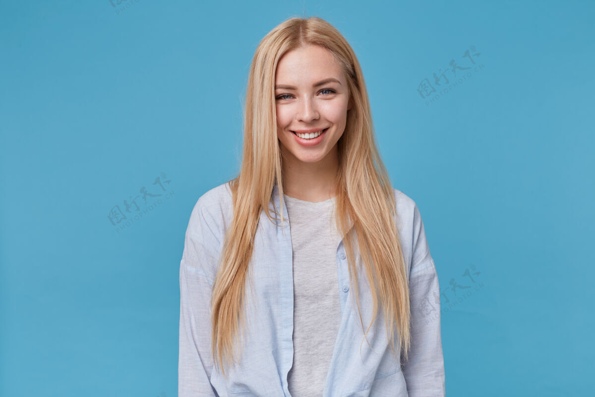 休闲年轻的金发女郎的肖像 随意的发型摆姿势 穿着蓝色衬衫和灰色t恤 在得到愉快的赞美后表现出积极的情绪女人头发灰色