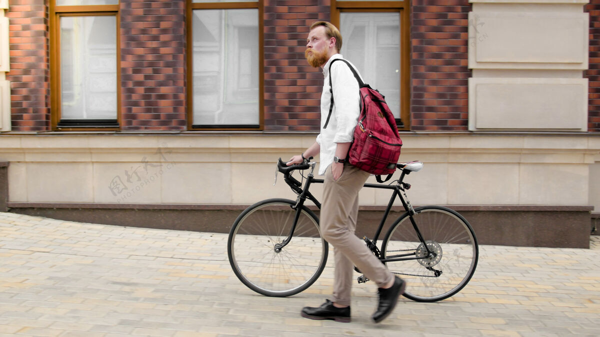 城市时髦的时髦男人 留着胡子 骑着自行车在城市街道上行走时尚优雅齿轮