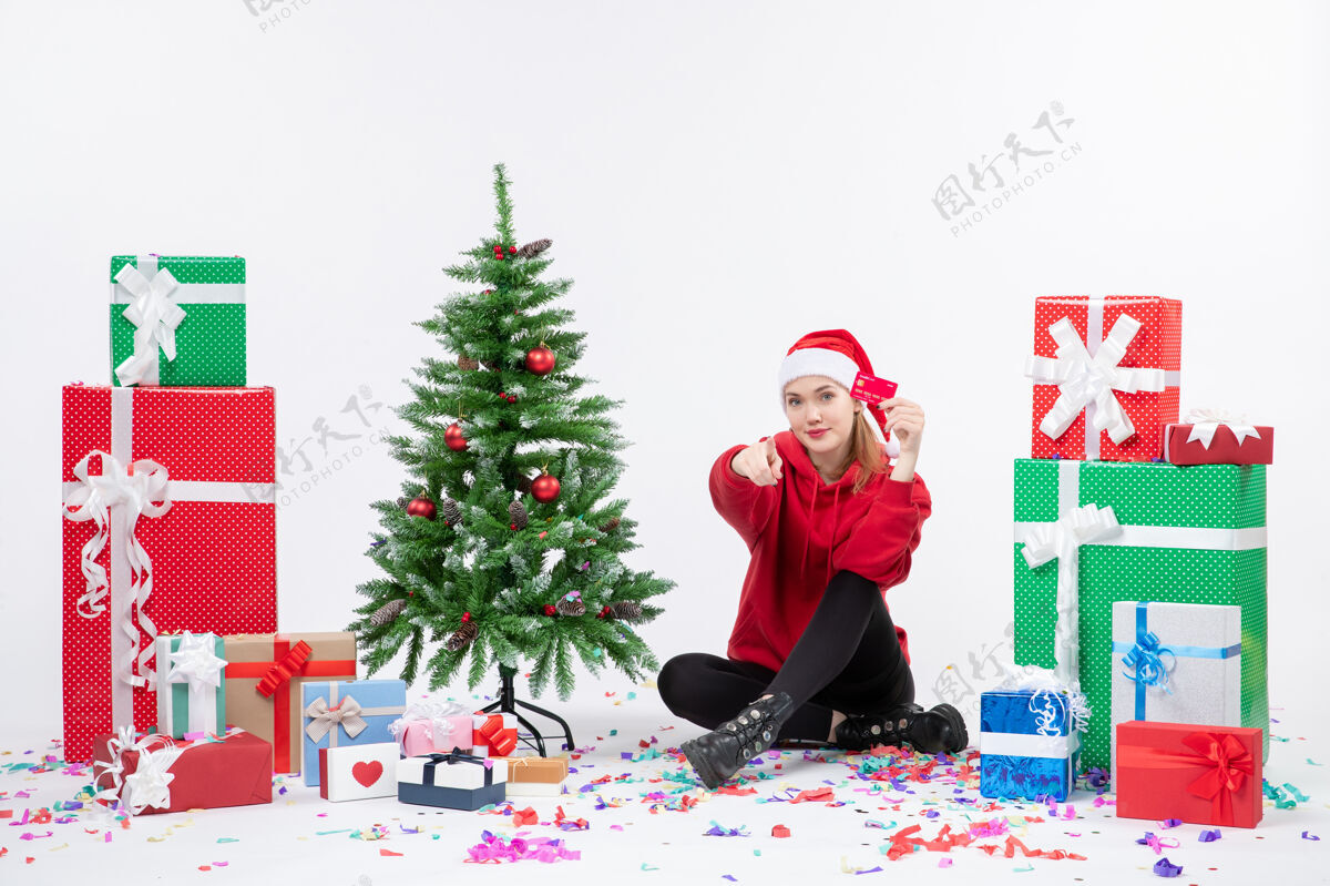 十二月正面图：年轻女子围坐在白墙上 手里拿着红色的银行卡情感快乐冬天