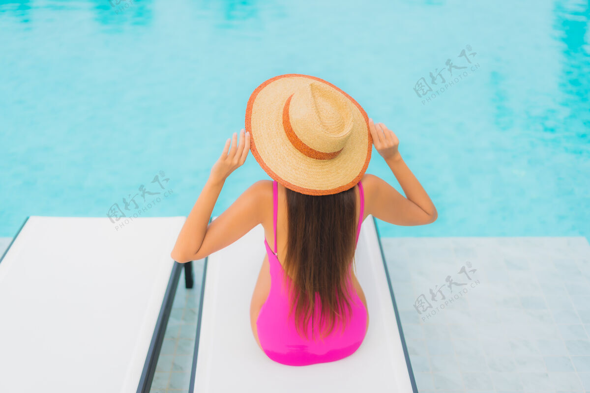 休闲肖像美丽的亚洲年轻女子放松微笑周围的室外游泳池在酒店度假村豪华游泳热带