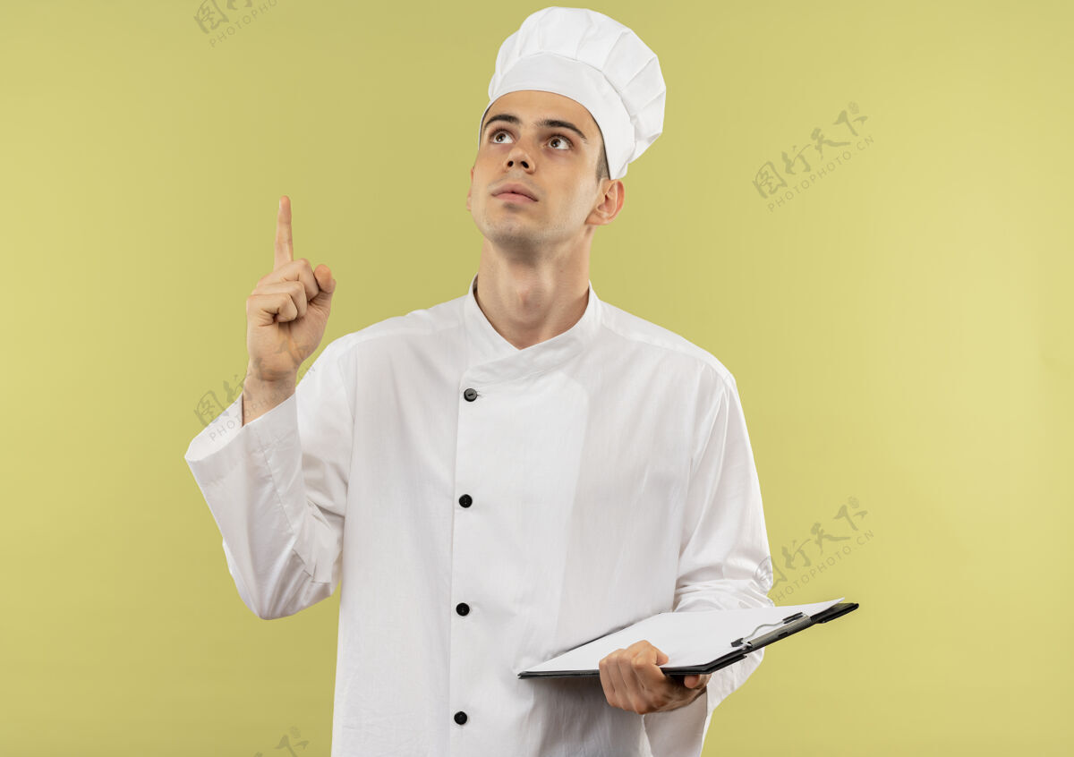 年轻看着上了年纪的男厨师穿着厨师制服 指着手指向上 拿着剪贴板贴在孤零零的绿墙上剪贴板厨师穿