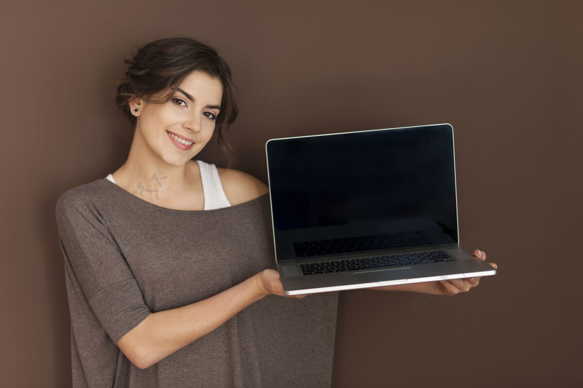 微笑微笑的女人展示当代笔记本电脑笔记本电脑呈现科技