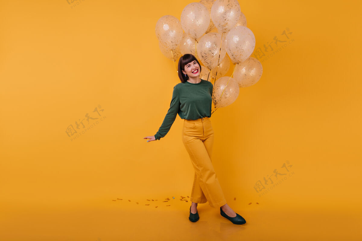 服装笑女人双腿交叉站立的全长肖像浪漫的生日女孩与金色气球跳舞的室内镜头肖像模特气球