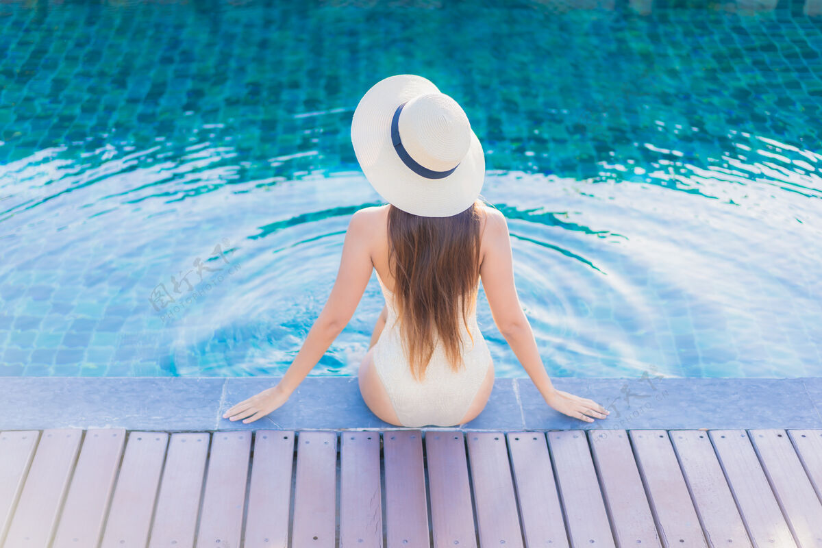 放松美丽的亚洲年轻女子在度假酒店的室外游泳池周围放松的肖像泳装放松休息