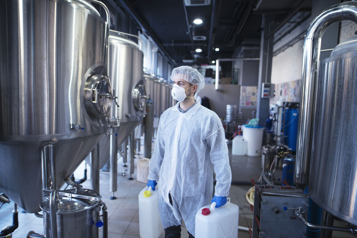 生产手握塑料罐的工业工人正准备在食品加工机中更换化学品实验室质量控制工程师