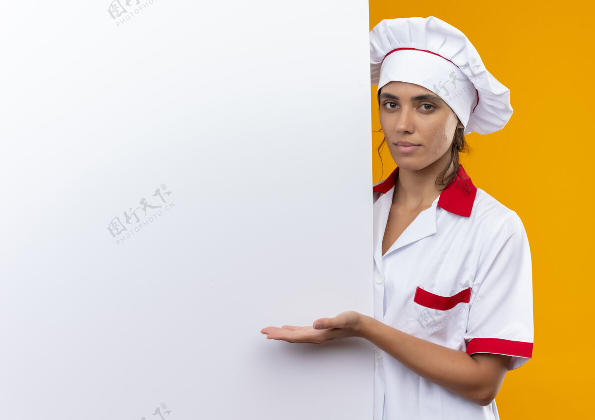 厨师身穿厨师制服的年轻女厨师手拿白色墙壁 在隔离的黄色墙壁上展示复制空间女年轻制服