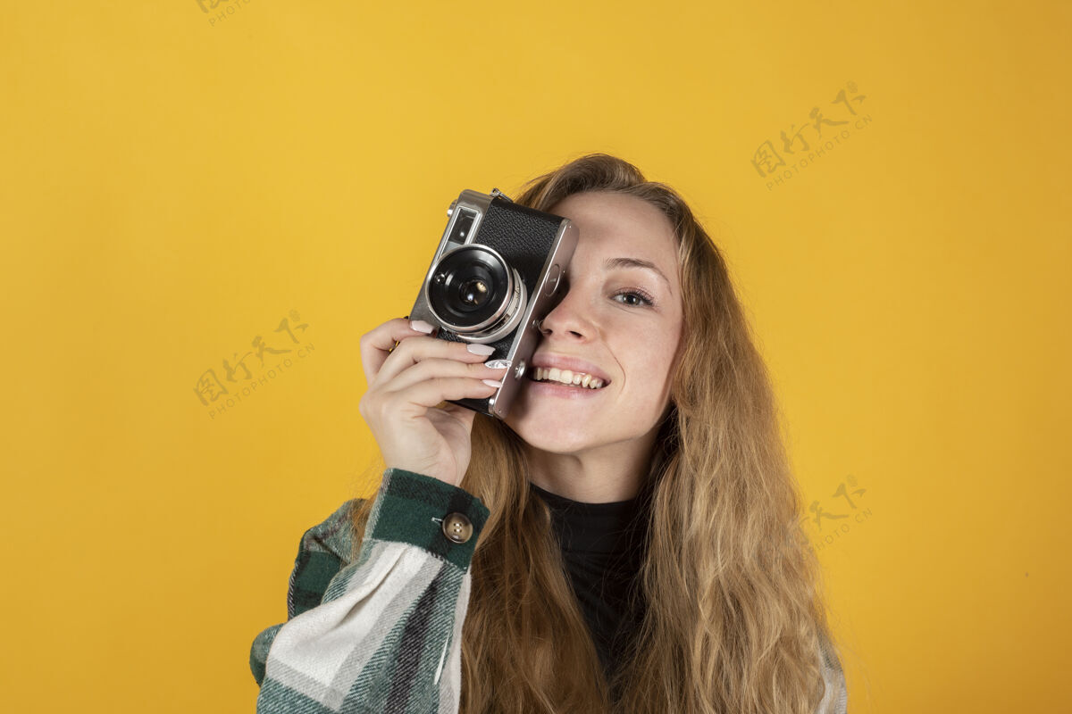人漂亮的金发女人拿着相机 黄色的欢乐漂亮摄影师