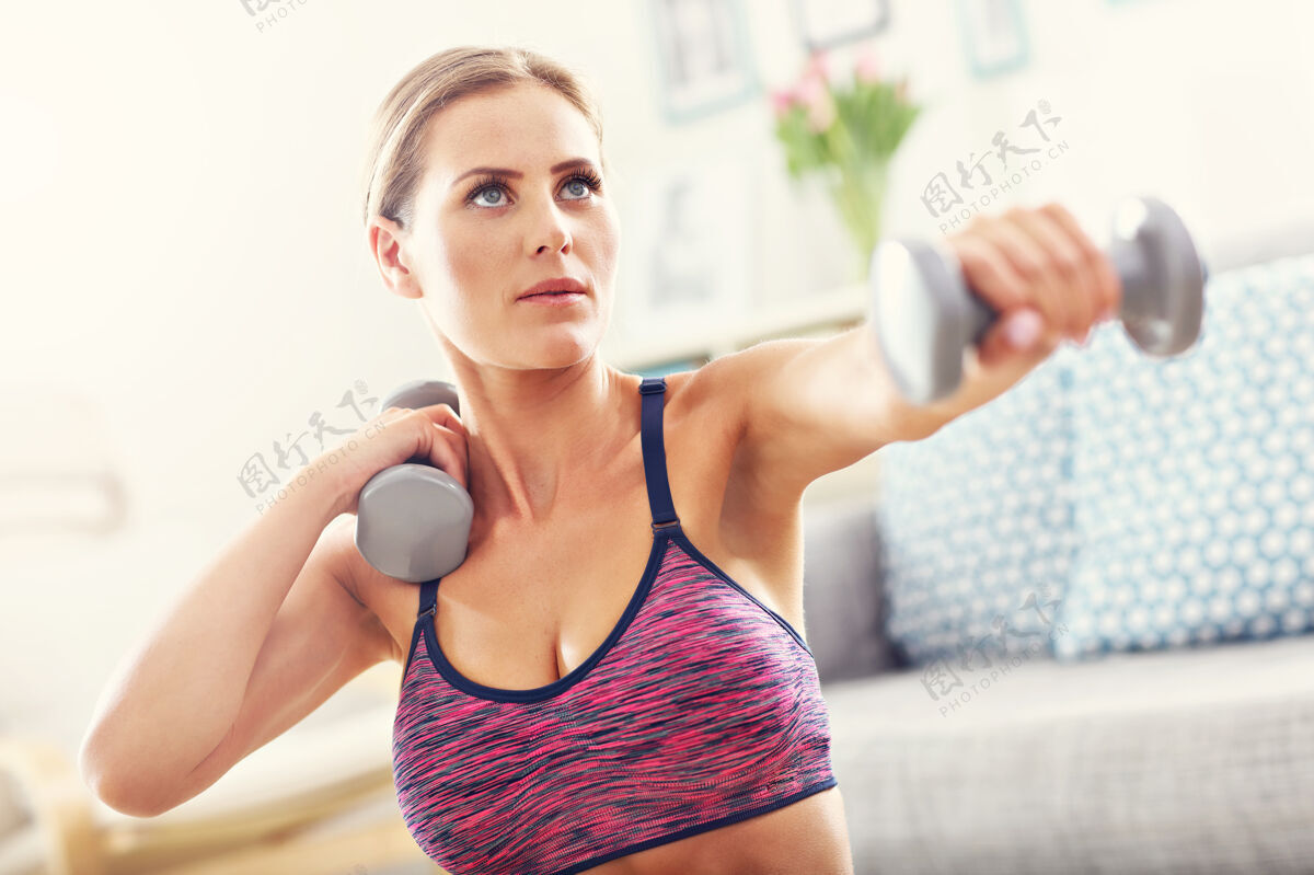 哑铃在家练习哑铃的女人努力健身运动员